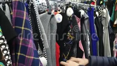 女人在商店里挑选衣服，女人在衣架上`衣服